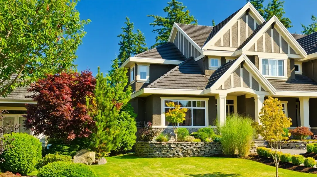 Exterior photo of a new two-story house with clean landscaping on a sunny day.